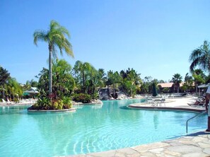 A large outdoor swimming pool surrounded by palm trees and tropical vegetation. - PARADISE FOUND!  LAKEFRONT FIRST FLOOR CONDO IN TROPICAL FALLING WATERS (Naples)