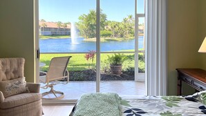 Una habitación con una cama, una silla y vistas a un lago y palmeras.