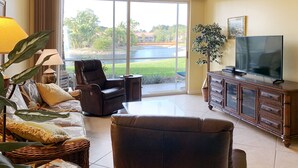 Sala de estar con sofá, sillón y televisión sobre un mueble de madera.