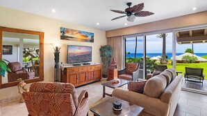 A spacious living room with a large TV, comfortable seating, a ceiling fan, and a view of the ocean. - REDUCED July & August!  ~ OCEAN FRONT Bay Villa- 25 G-5 ~ Platinum Maui Vacations (Lahaina)