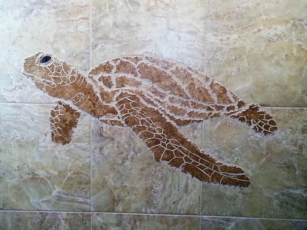 A mosaic of a sea turtle on a tiled wall.