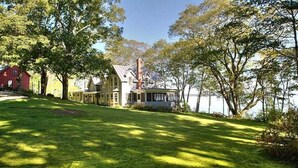 Uma casa com um gramado grande e vista para um lago.