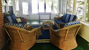 Varanda coberta com móveis de vime, mesa de bilhar e vista para o exterior.