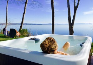 A person relaxing in a hot tub with a lake view. - Gorgeous Waterfront Estate In Historic Bayside (Northport)