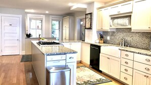 Uma cozinha moderna com bancadas de granito, eletrodomésticos de aço inoxidável e armários em tons claros.