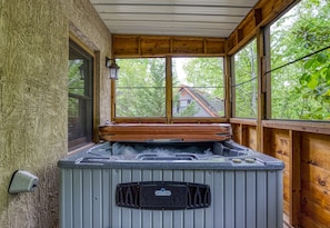 A hot tub with a wooden roof and windows, surrounded by a stone wall.