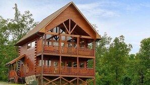 Eine zweistöckige Blockhütte mit Balkon, umgeben von Bäumen.