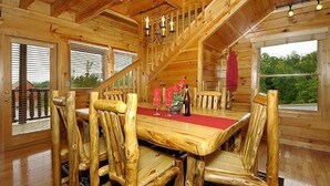 Ein Essbereich mit Holzboden, einem Tisch, Stühlen, einer Deckenleuchte und Blick ins Freie.