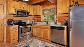 Una cocina con armarios de madera, electrodomésticos de acero inoxidable y un tapete con estampado de piedra.