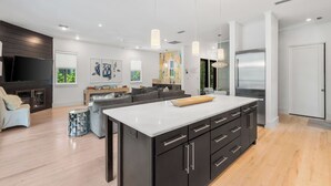 A modern kitchen with a large island, dark cabinetry, and stainless steel appliances. - Blissful days, barefoot nights at Beach Bliss / Private Pool / Gulf Front Beach Club / 6 Bikes (Santa Rosa Beach)