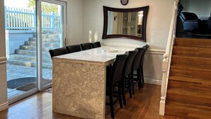 A kitchen with a marble countertop, black bar stools, a clock on the wall, and a view of a blue gate outside. - Glorious gateway 4 bedroom lake home- Discount Rates!! (Hot Springs)