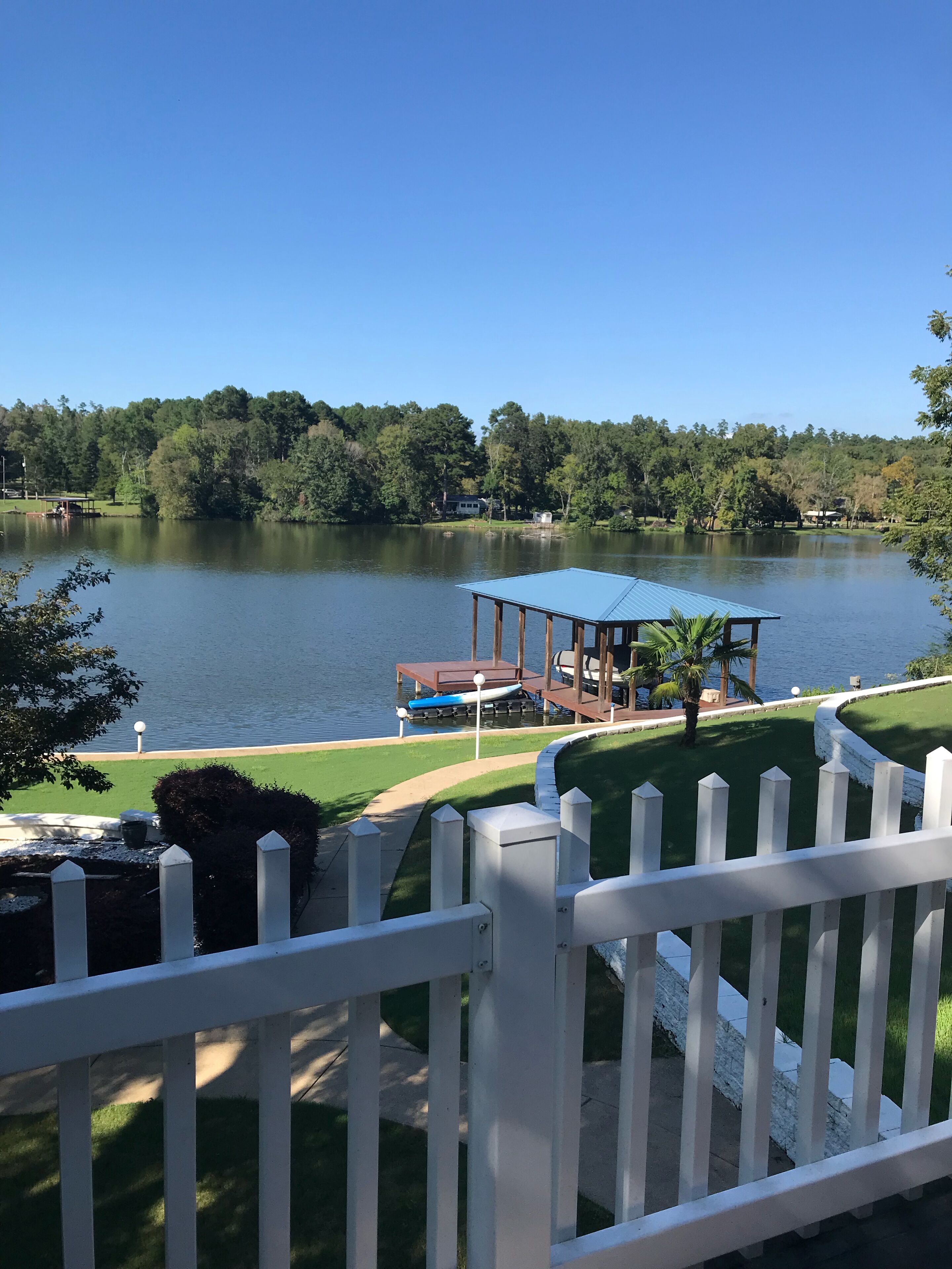 A lakeside view with a gazebo, dock, and boats.