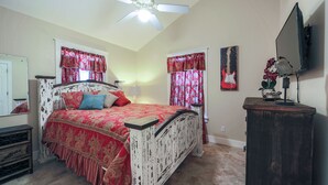 A bedroom with a bed, a ceiling fan, a TV, and a dresser. - Abby's Place 4 - Rocking On Route 66 (Fredericksburg)