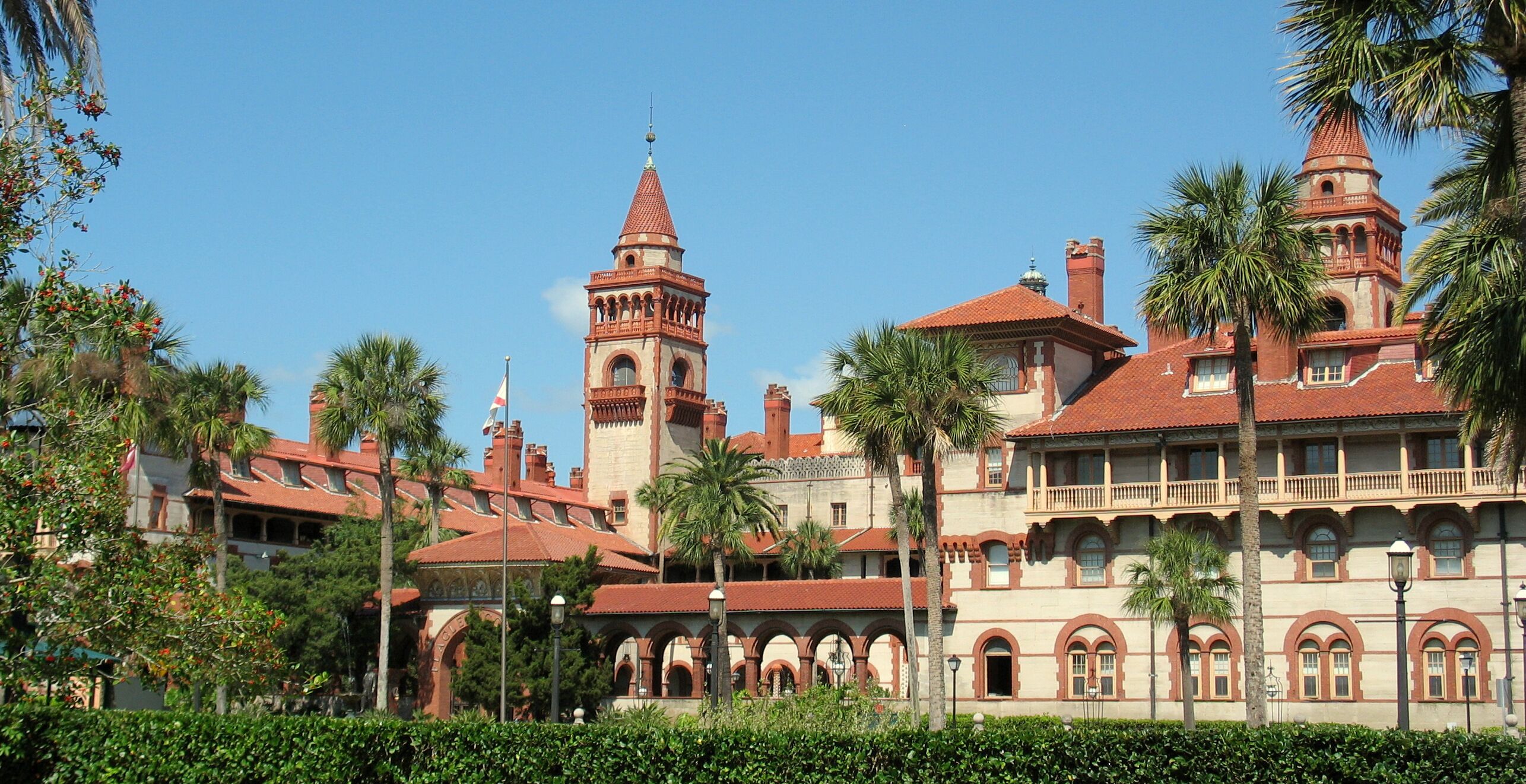 A historic building with arched windows, a central tower, and a red-tiled roof.