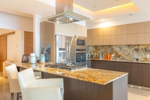 A modern kitchen with a central island, stainless steel appliances, and a granite countertop.