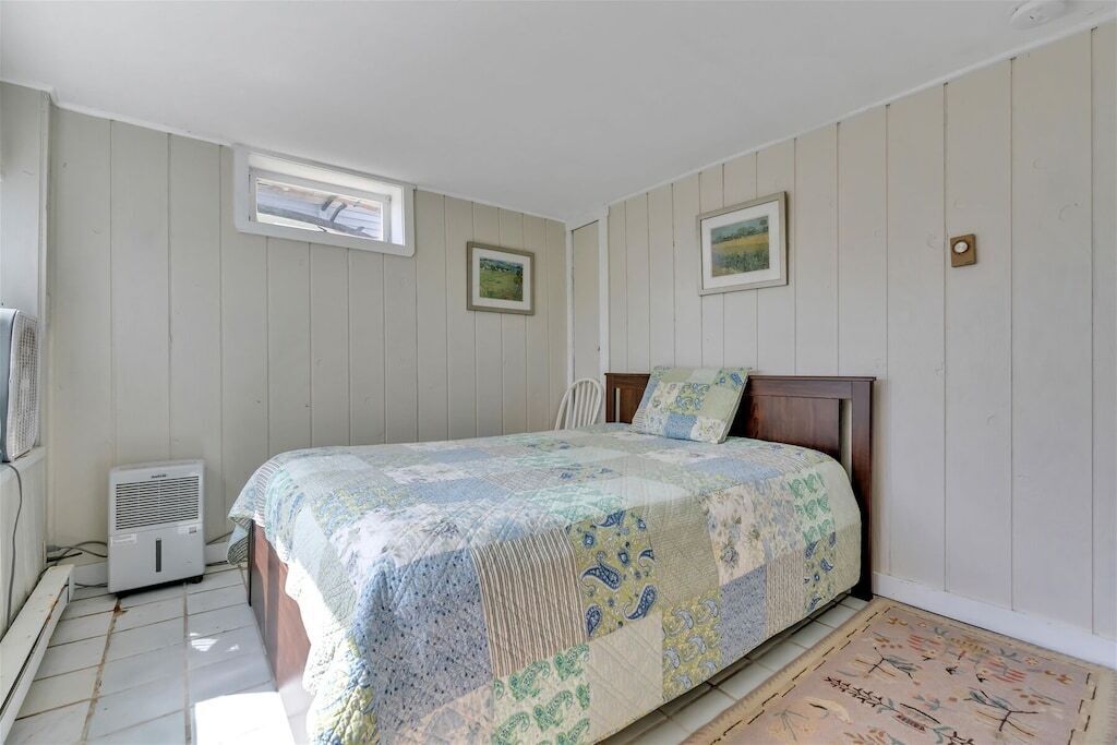 A bedroom with a bed, two windows, a radiator, and a rug.