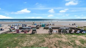 En strand med liggestole og borde, et telt og udsigt til havet.