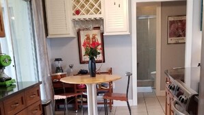 Una cocina con armarios de madera, una mesa de comedor con sillas, un ventilador de techo y suelo de baldosas.