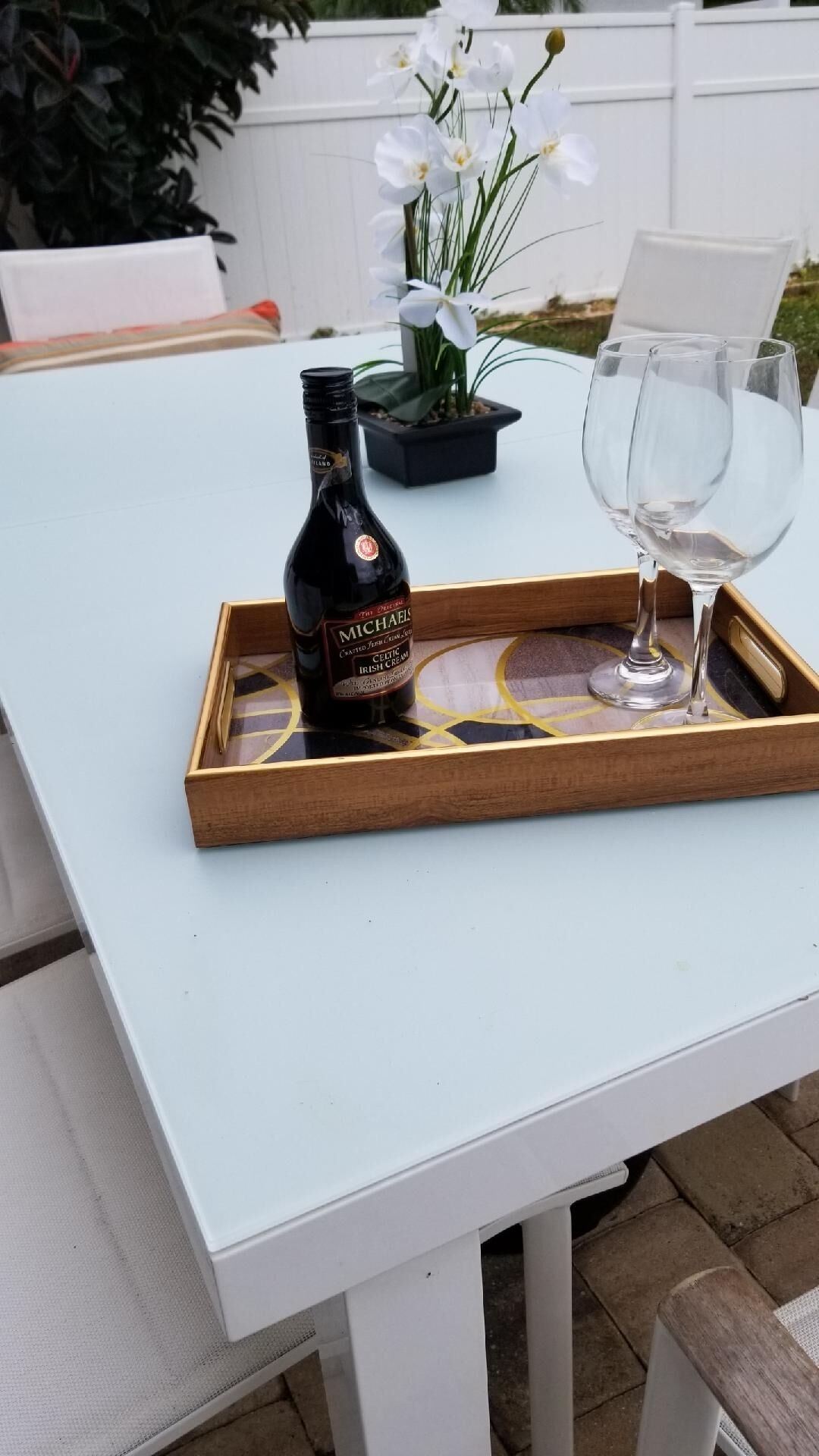 Una botella de Michael's Irish Cream sobre una bandeja con un vaso en una mesa blanca.