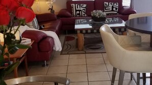 Una sala de estar con un sofá rojo, una mesa redonda y un ventilador de techo.