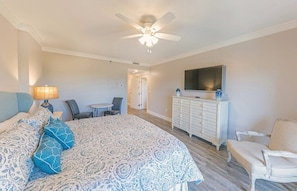 A hotel room with a bed, a desk, a chair, a dresser, and a television.