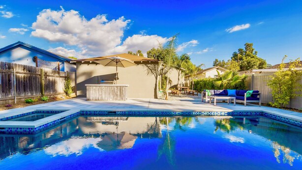 Ein Garten mit Swimmingpool, Grillplatz und Terrasse mit Gartenmöbeln.