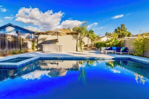 Un jardin avec une piscine, un espace barbecue et une terrasse aménagée avec du mobilier d’extérieur.