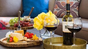 Ein Esstisch mit Käseplatte, Trauben und Weingläsern, platziert in einem Wohnzimmer mit Sofa und Zierkissen.