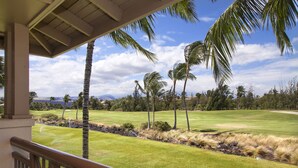 A view from a balcony overlooking a golf course with palm trees and a clear sky. - Excellent for couples or families. Right on the Golf Course. (Waikoloa)