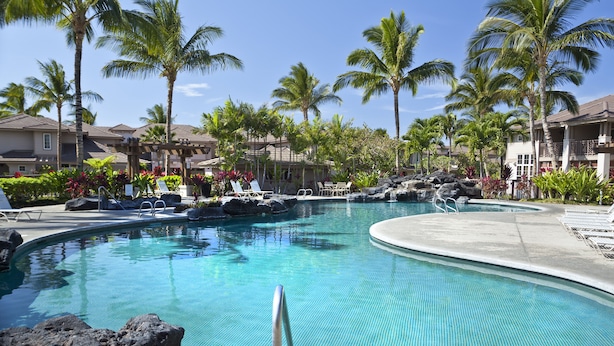 A pool with lounge chairs and palm trees. - Excellent for couples or families. Right on the Golf Course. (Waikoloa)