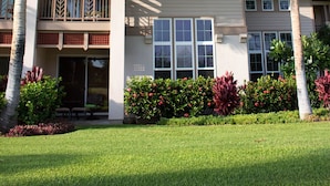 A two-story house with a balcony, surrounded by palm trees and well-maintained gardens. - Excellent for couples or families. Right on the Golf Course. (Waikoloa)