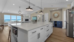 A spacious kitchen with a large island, white cabinetry, and a view of the ocean. - My Island Pad: Beachfront Home, Fully Renovated (Pensacola Beach)
