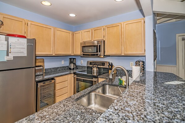 A modern kitchen with wooden cabinets, stainless steel appliances, granite countertops, and a built-in oven.
