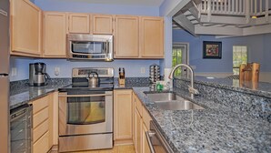 A modern kitchen with wooden cabinets, stainless steel appliances, granite countertops, and a built-in oven.