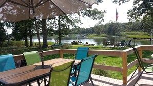 Une terrasse avec des sièges extérieurs, une vue sur un lac et des tables de pique-nique.