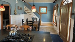 Une cuisine équipée d’une cuisinière à gaz, de chaises en bois, d’une table à manger et d’un escalier menant à un deuxième étage.