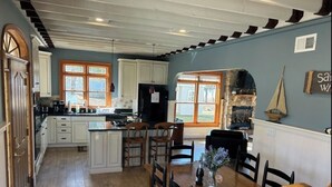 Une cuisine spacieuse avec des meubles blancs, un îlot central et un coin repas comprenant une table et des chaises en bois.
