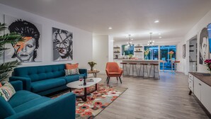 Een moderne woonkamer met een blauwgroene bank, een bijzettafeltje en een kleurrijk vloerkleed.