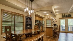 A kitchen with wooden cabinets, a dining table with benches, and a built-in island with a sink. - Outdoor pool access, Private putt putt-Close to Pigeon Forge-outdoor kitchen-game room and  more.... (PIGEON)