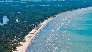 Luchtbeeld van een kustgebied met strand, dicht bos en een rivier.