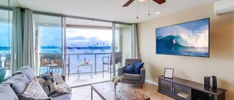 A modern living room with a sofa, coffee table, and a painting of a wave.