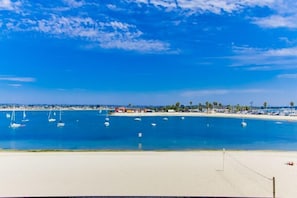 A coastal view with a sandy beach, boats, and a clear blue sky.