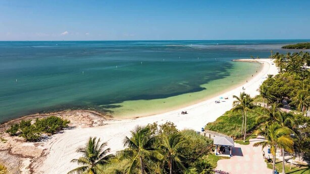 A beach with clear turquoise water, a sandy shore, and palm trees. - Marathon 4BR | Pool, Dock & Near Sombrero Beach (Marathon)