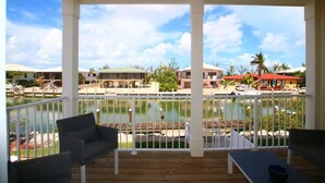A covered outdoor area with a view of a marina, wooden deck, and white railings. - Marathon 4BR | Pool, Dock & Near Sombrero Beach (Marathon)