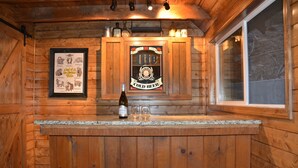 A wooden bar area with a framed sign for 'Lite Cold Beer', two stools, and a bottle of beer on the counter.