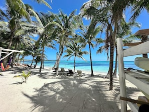 A beach with palm trees, lounge chairs, and a wooden structure. - BEACHFRONT VILLA ON WHITE SAND BEACH AND CHEF SERVICE AVAILABLE (Soliman Bay)