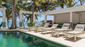 Un espace aménagé au bord de la piscine, avec des chaises longues et une vue sur l’océan.