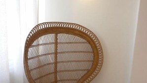 A wicker chair with a striped cushion in a room with a light fixture on the wall. - Gorgeous 2.5 Bdrm Apt. in Jerusalem (Jerusalem)