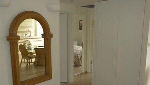 A hallway with a wooden-framed mirror, a dining area with a table and chairs, and a bedroom with a bed and curtains. - Gorgeous 2.5 Bdrm Apt. in Jerusalem (Jerusalem)