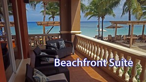 A beachfront suite with wicker furniture, a view of the ocean, and a wooden railing. - ONLY Beachfront Suite @ Infinity Bay Resort - 24hr Service, Pools, Spa, Luxury! (West Bay Beach)